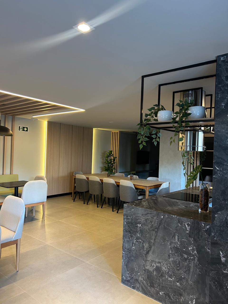 Área gourmet com mesa longa de madeira e iluminação pendente